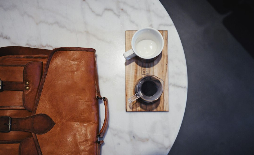 Overhead view of a modern meeting table with laptop, notebook and coffee
